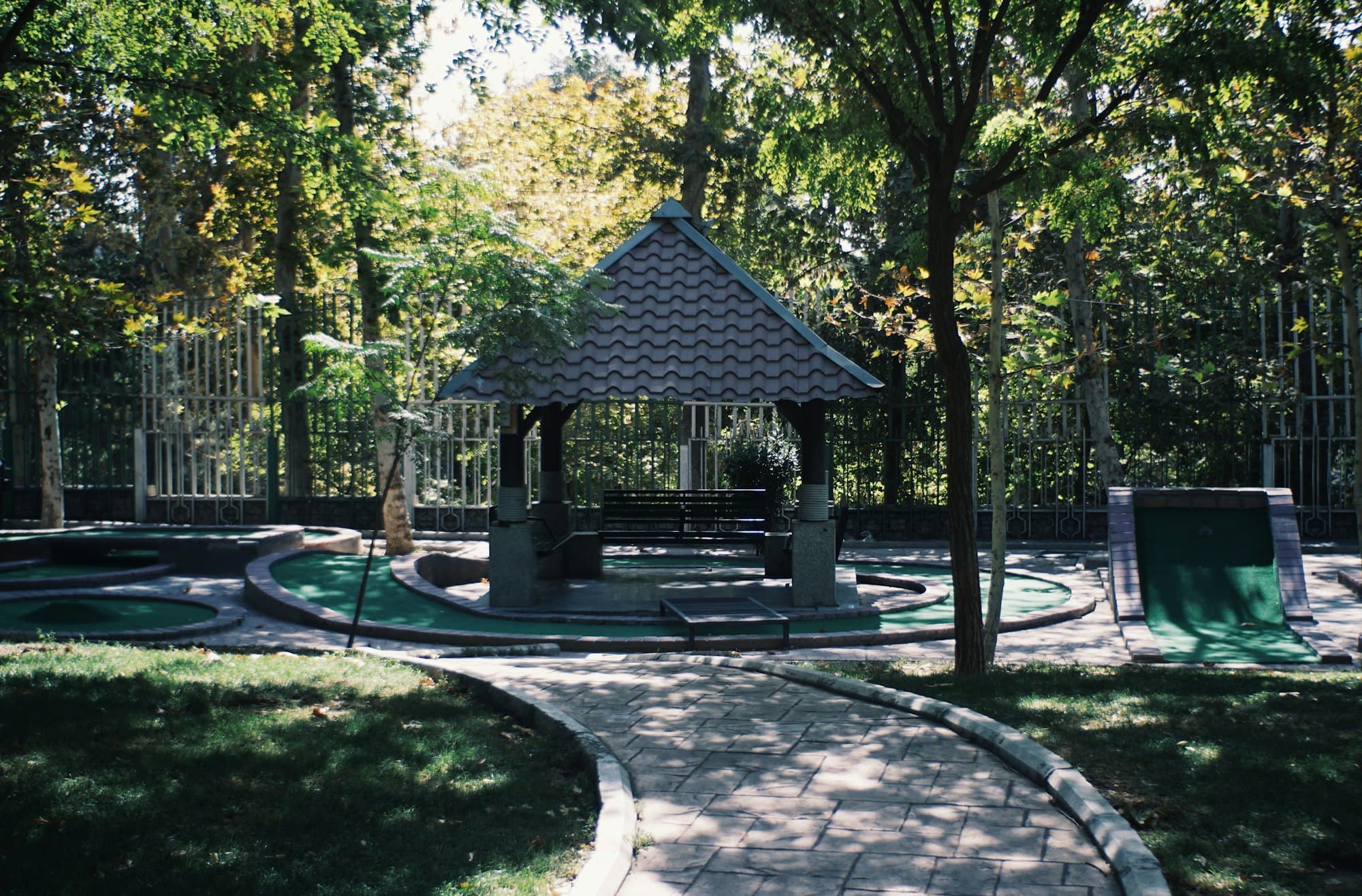 A mini golf course with a gazebo and trees at golden hour.